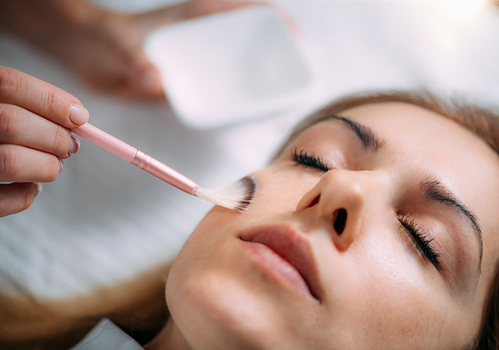 Woman getting a chemical peel brushed onto her cheek