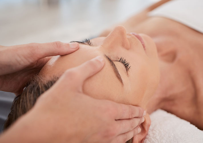 Woman having her forehead massaged during her facial